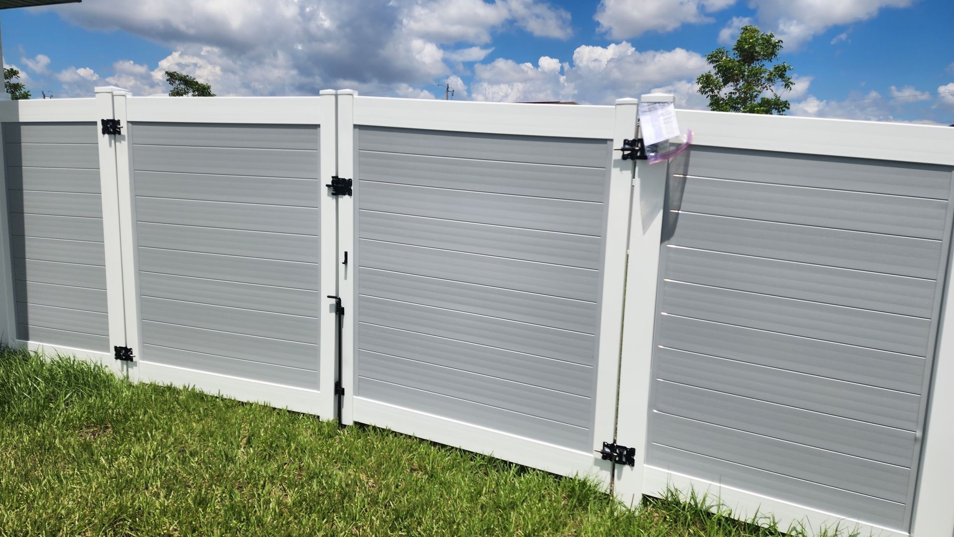 A white fence with a gate is sitting on top of a lush green lawn.