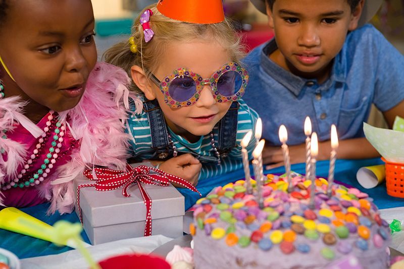 A group of children are blowing out candles on a birthday cake.