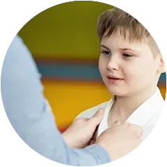 a woman is helping a young boy put on his gi