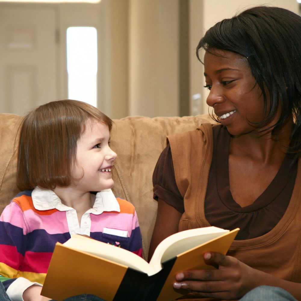 A woman is reading a book to a little girl