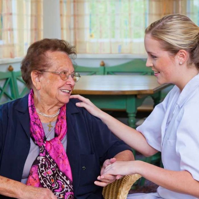 A nurse is putting her hand on an older woman 's shoulder