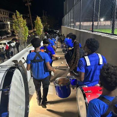 a group of marching band members are standing in front of a sign that says son yards