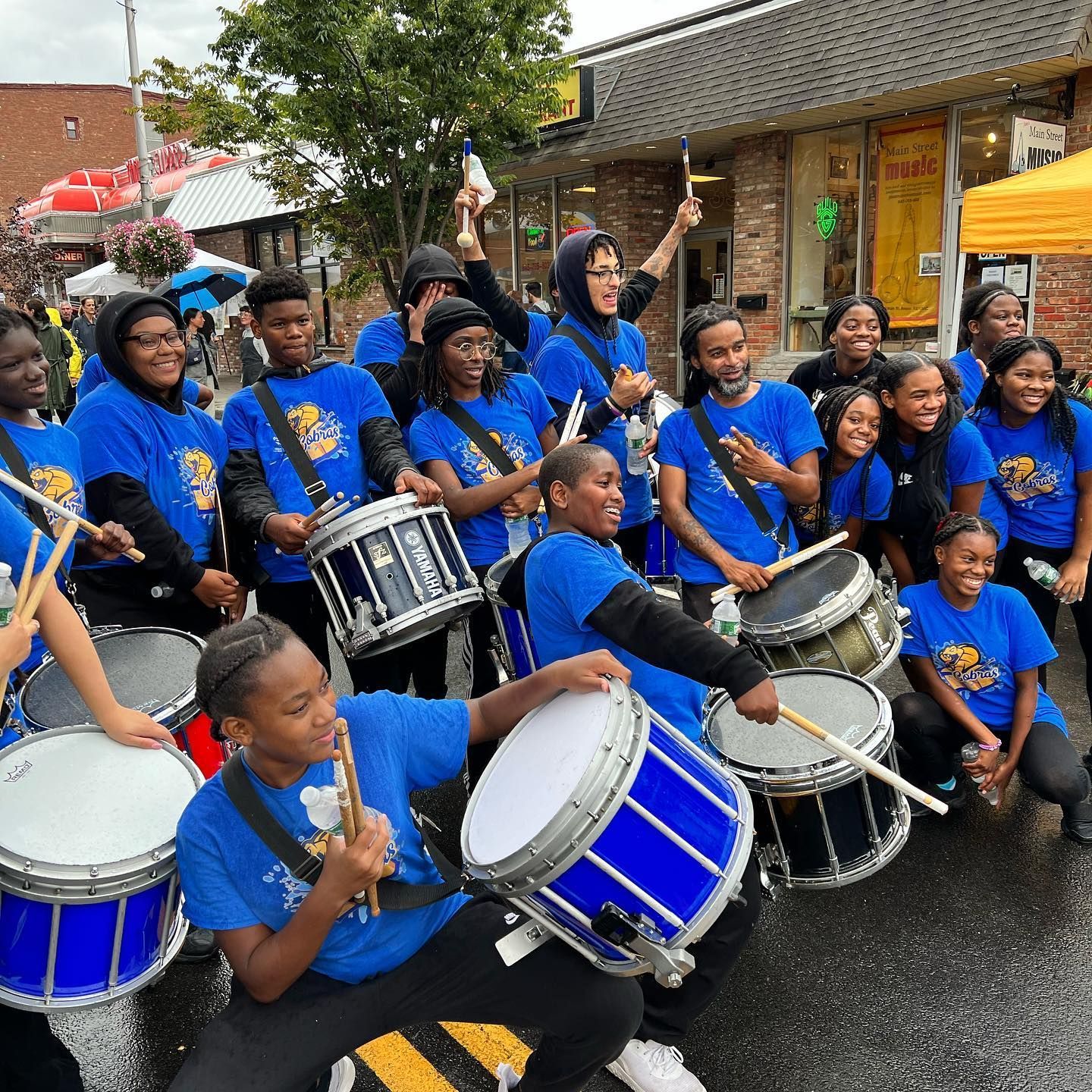 a group of people in blue shirts are playing drums