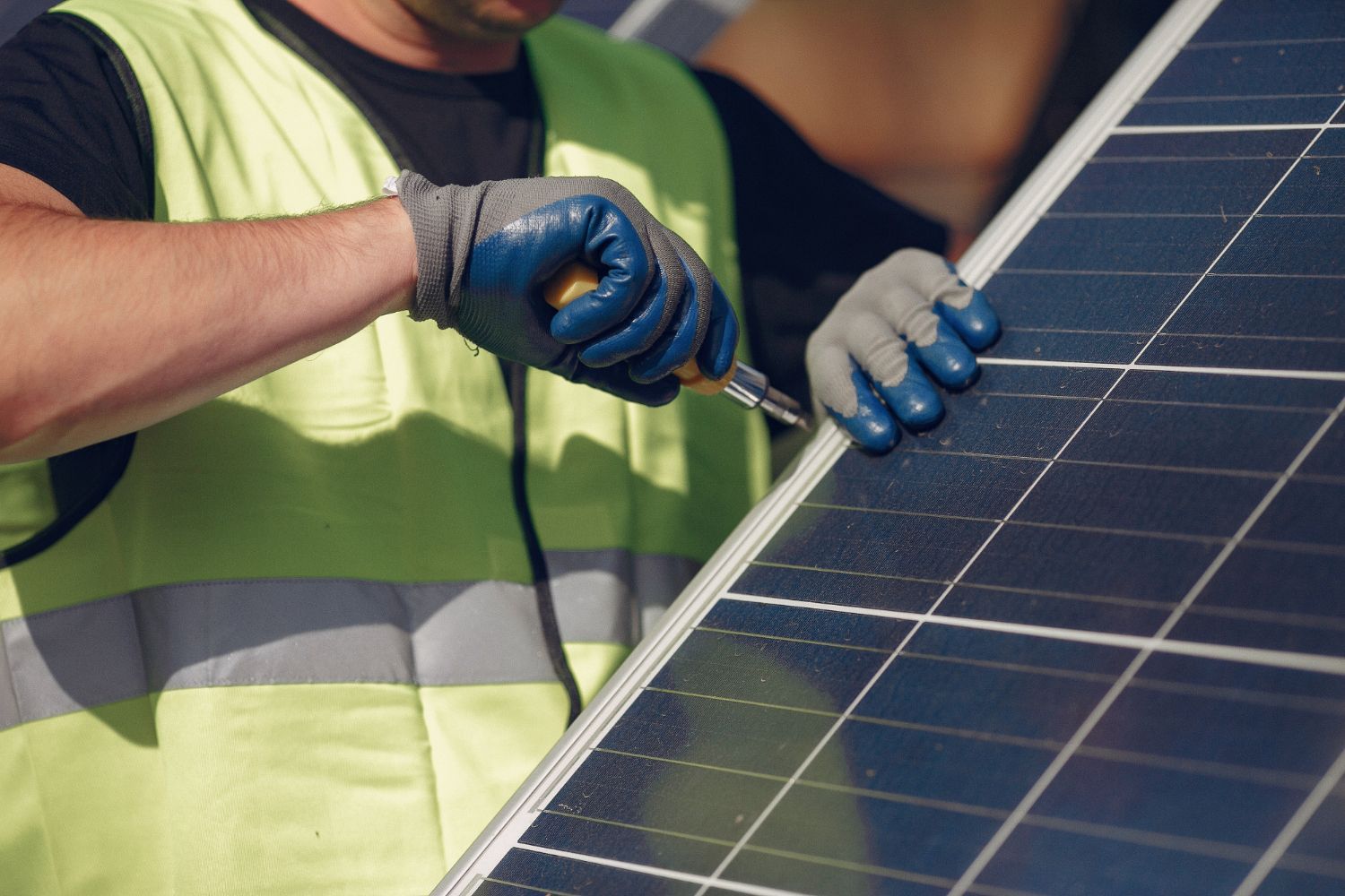 A man is working on a solar panel with a screwdriver.