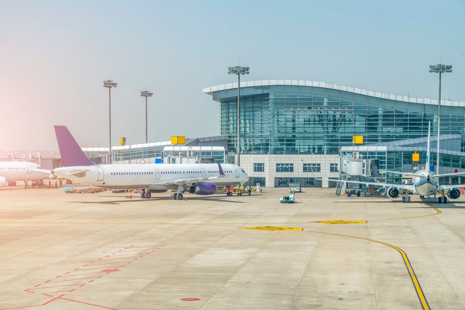 A purple and white airplane is parked on the tarmac of an airport.