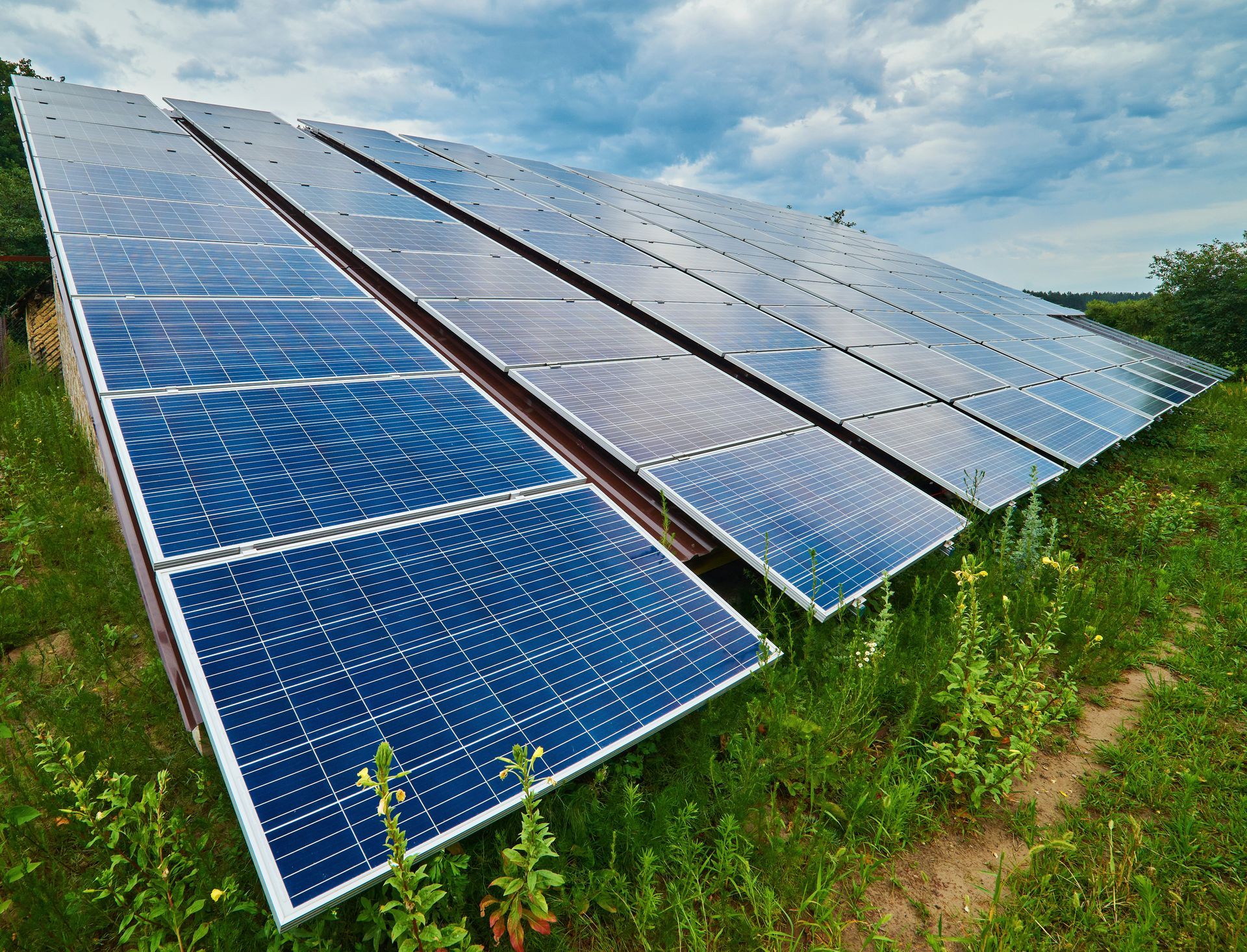 A row of solar panels are sitting in a grassy field.