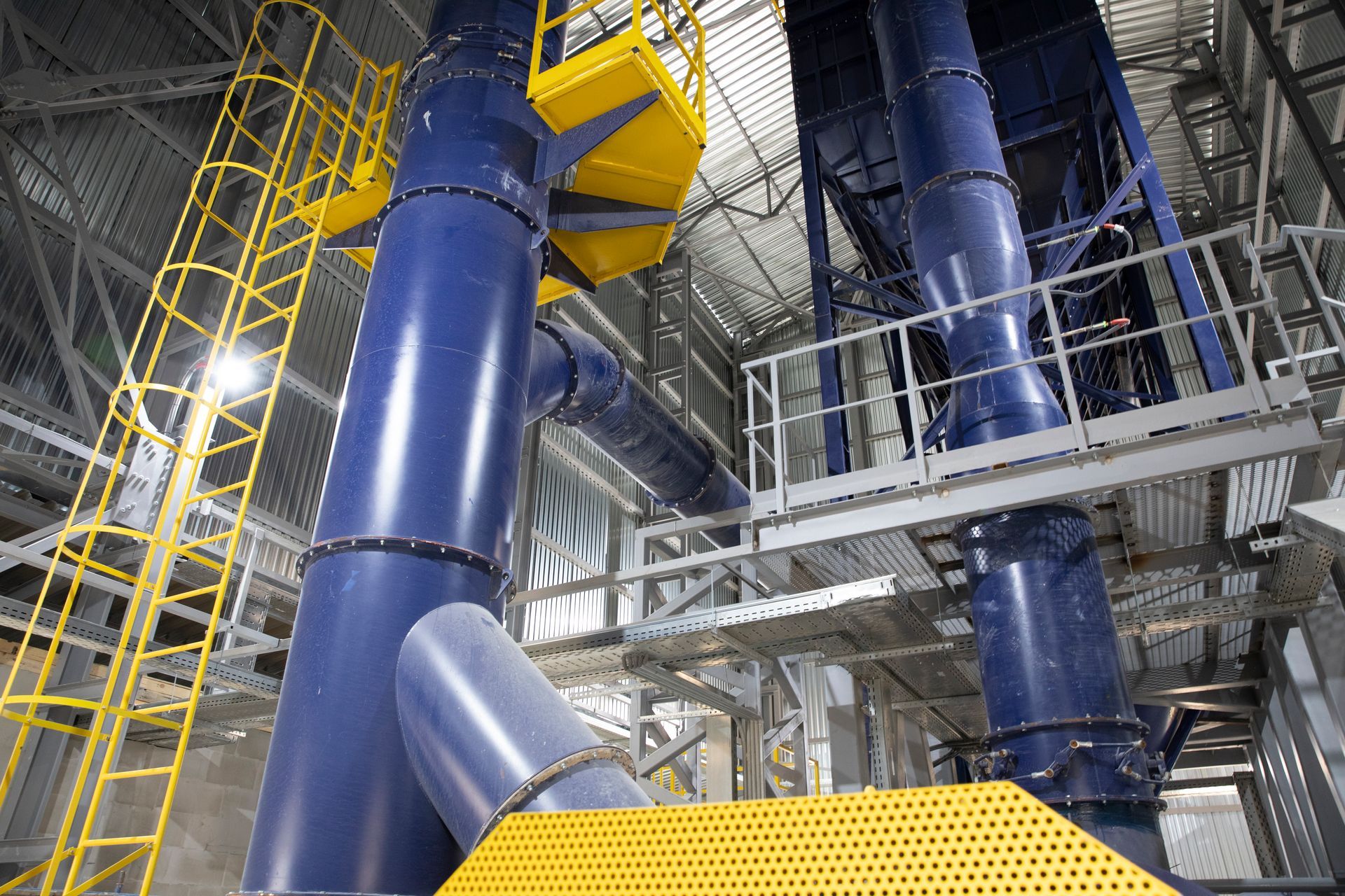 A factory with a lot of blue pipes and stairs