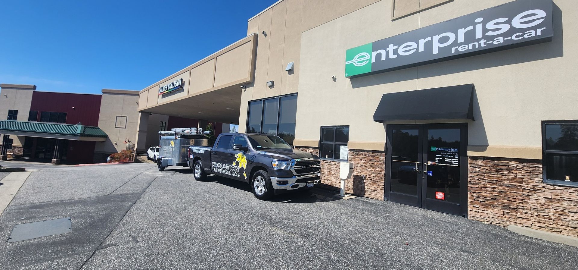 Evolution Electric commercial work truck towing a trailer parked outside an Enterprise business 