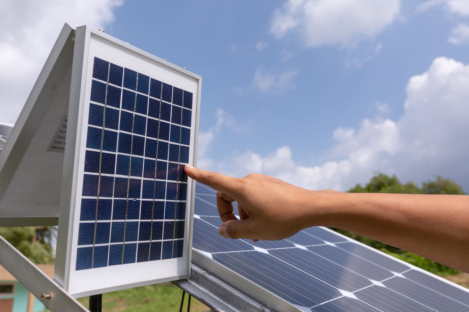 A person is pointing at a solar panel with their finger.