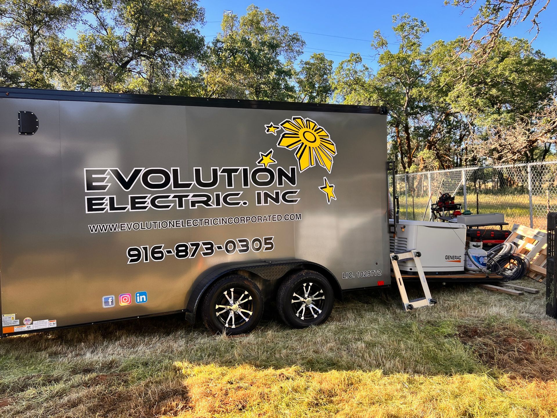 A trailer for evolution electric inc is parked in the grass.