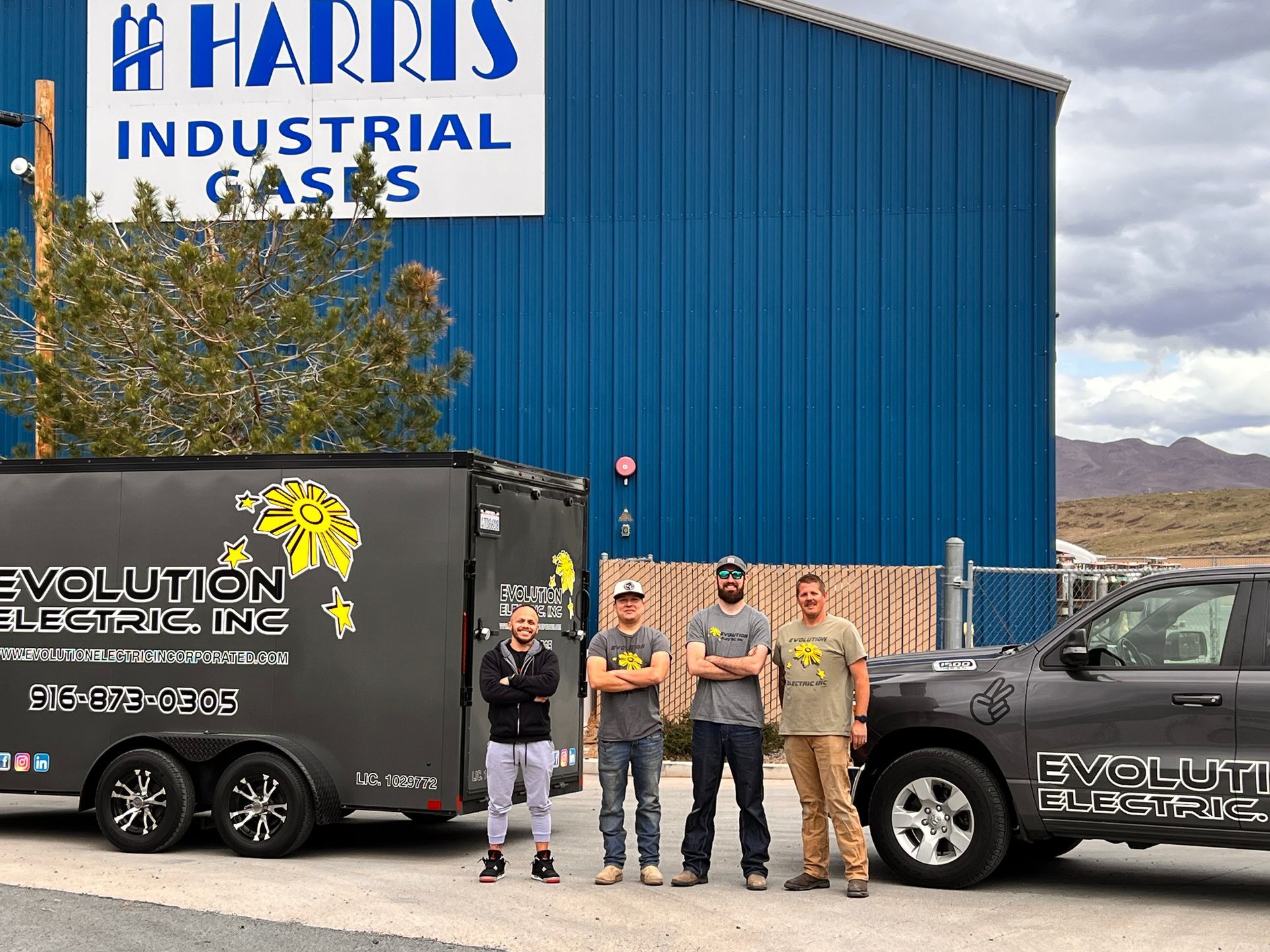 A group of men are standing in front of a truck and trailer.