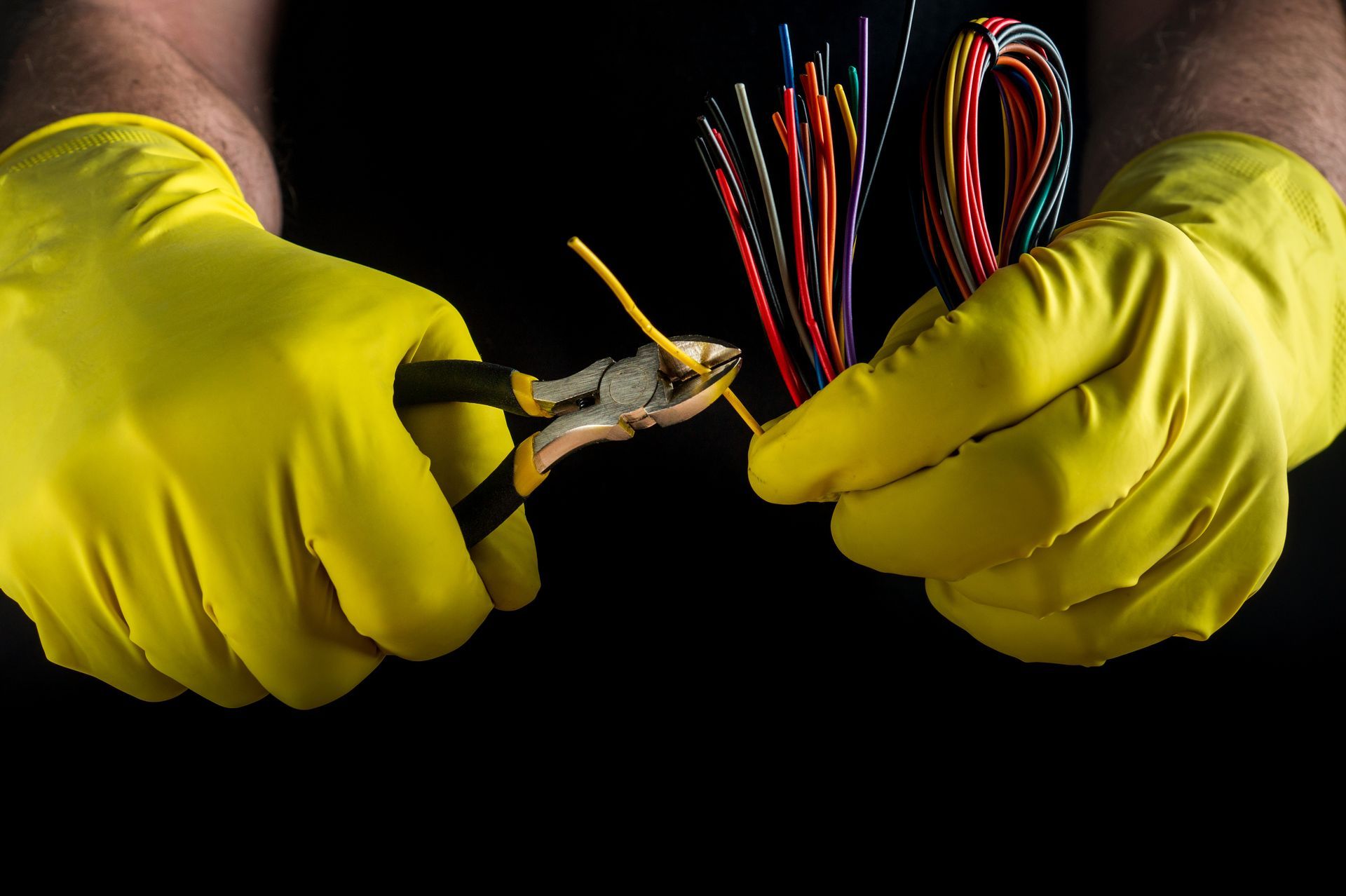 hands hold wire cutters in a close-up of wires
