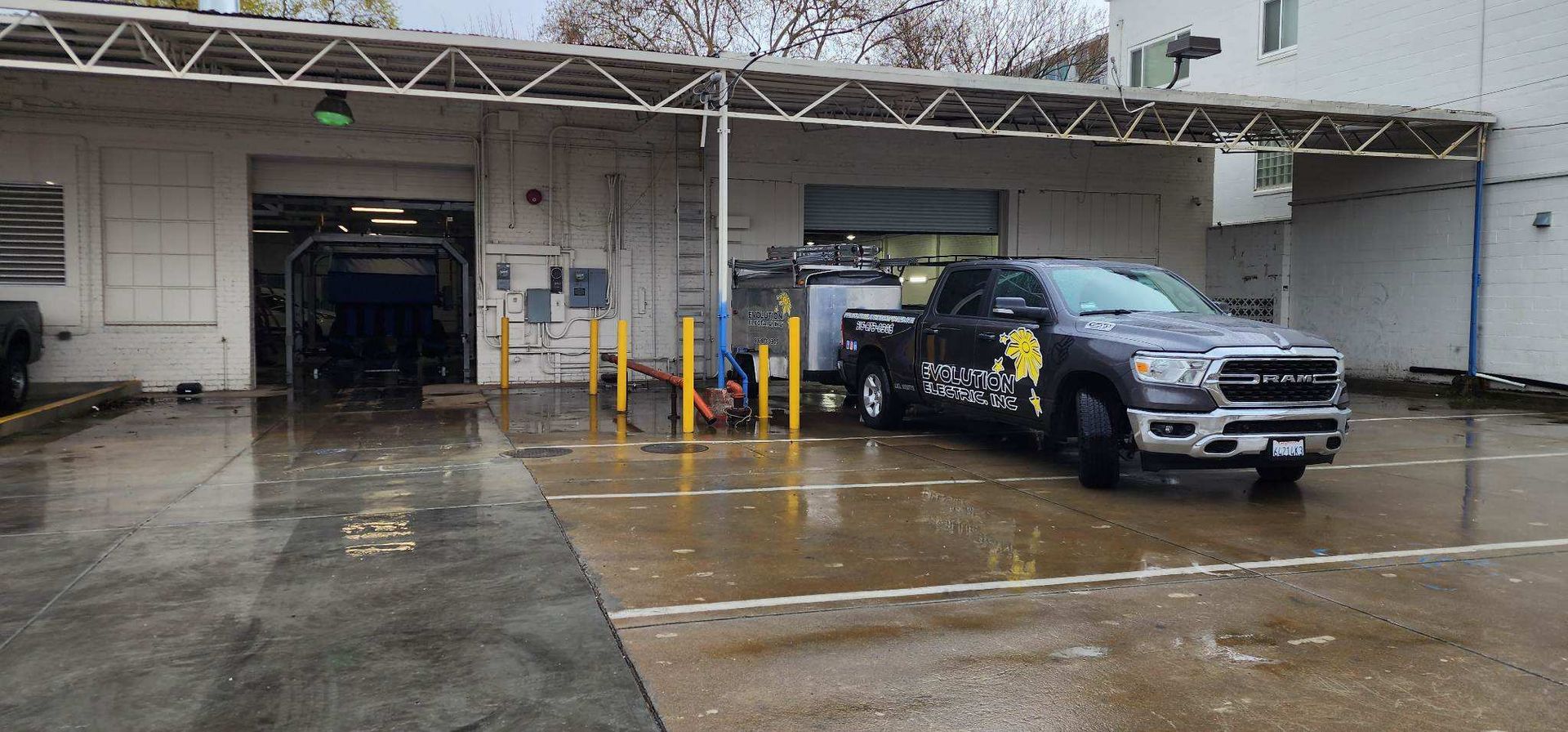 A truck parked at a car wash, it is raining.