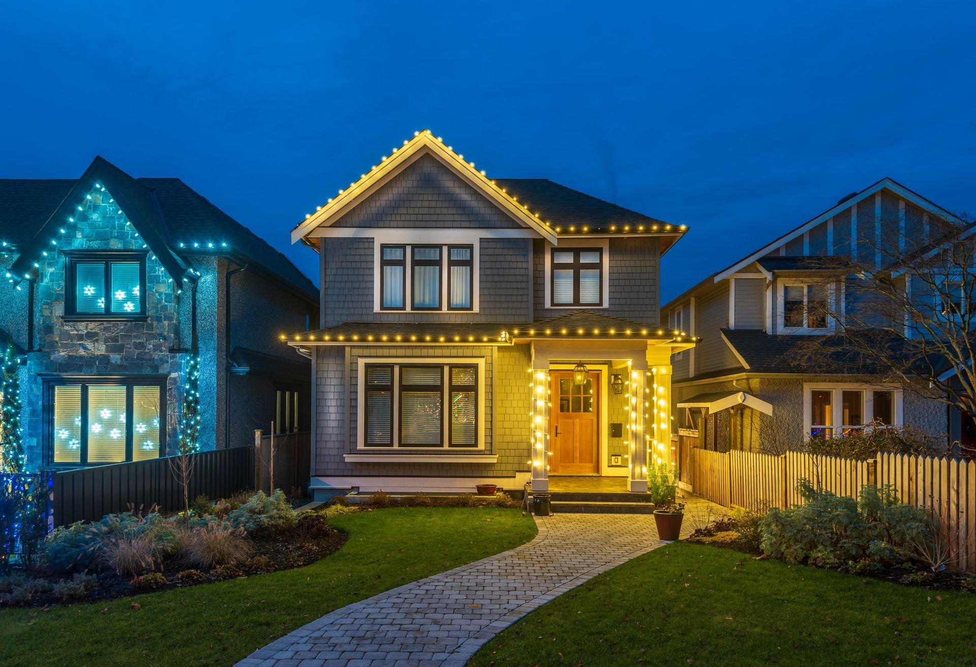Houses decorated with holiday lights at dusk.