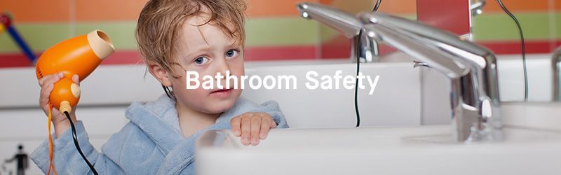 A little boy is holding a hair dryer in a bathroom.