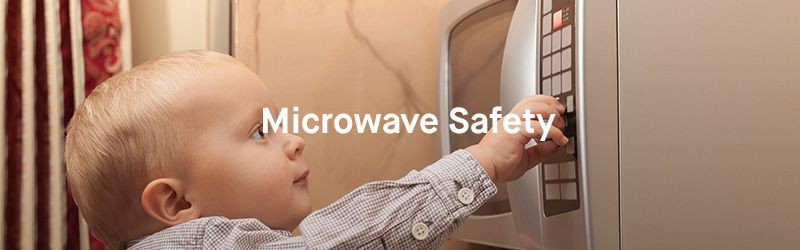 A baby is reaching into a microwave oven.