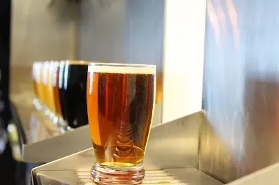A glass of beer is sitting on a metal shelf.