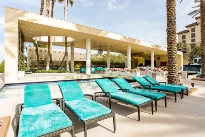 A row of blue lounge chairs are sitting next to a swimming pool.