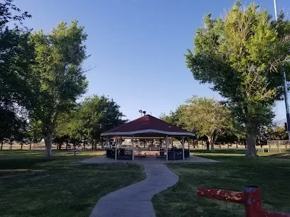 There is a gazebo in the middle of a park surrounded by trees.