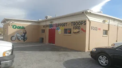 Two cars are parked in front of a building that says troops food
