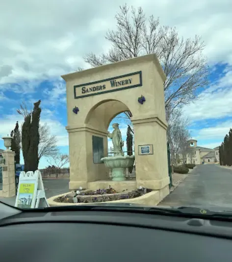 A car is driving past a stone archway that says sandras winery
