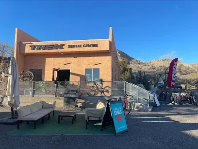 A bicycle is parked in front of a trek rental center.