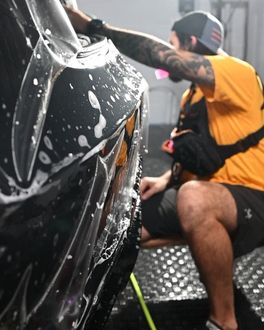 Person applying film to a car; the person is spraying soapy water.
