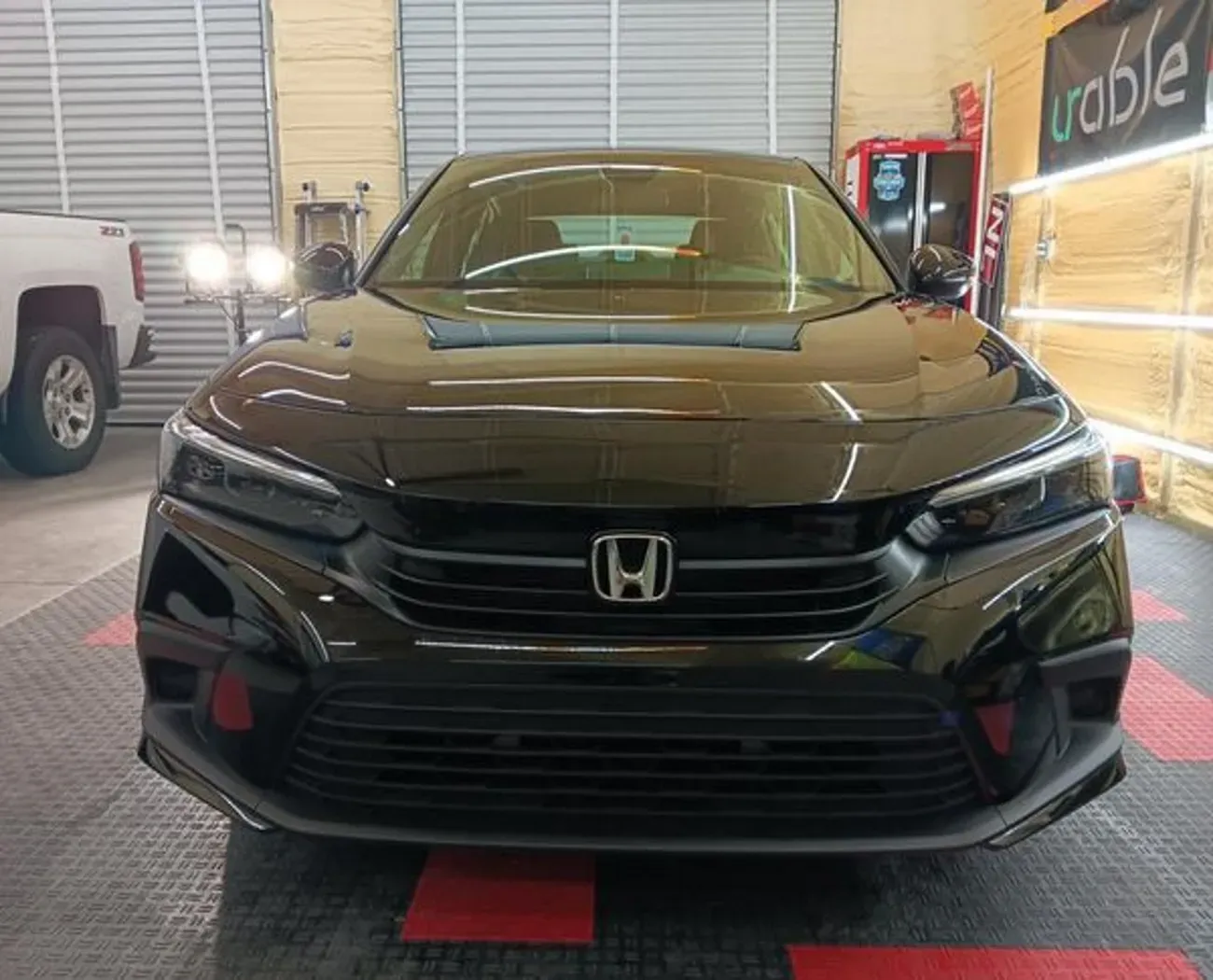 A black honda civic is parked in a garage.