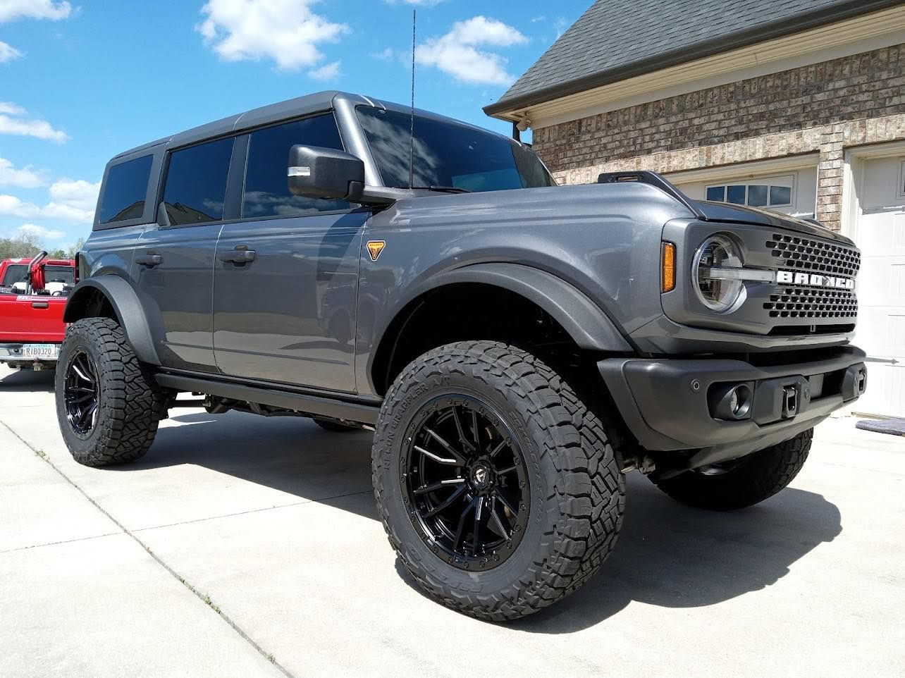 a ceramic coated ford bronco is parked in front of a garage