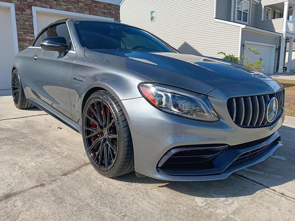 a mercedes c63 amg is parked in a driveway in front of a house .