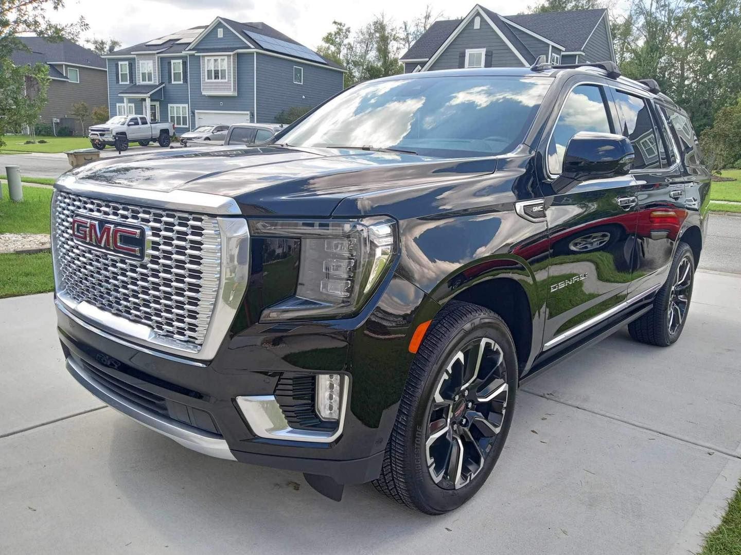 a black gmc denali suv is parked in front of a house