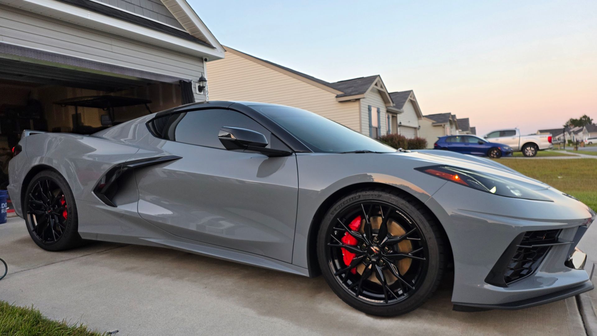 Gray sports car with black accents and red brake calipers parked in a driveway.