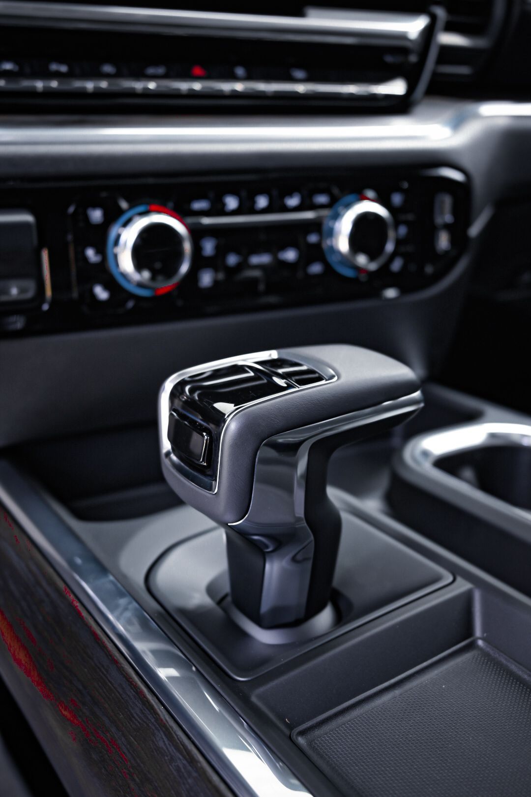 Automatic gear shift lever in a car's center console; dashboard controls visible in the background.