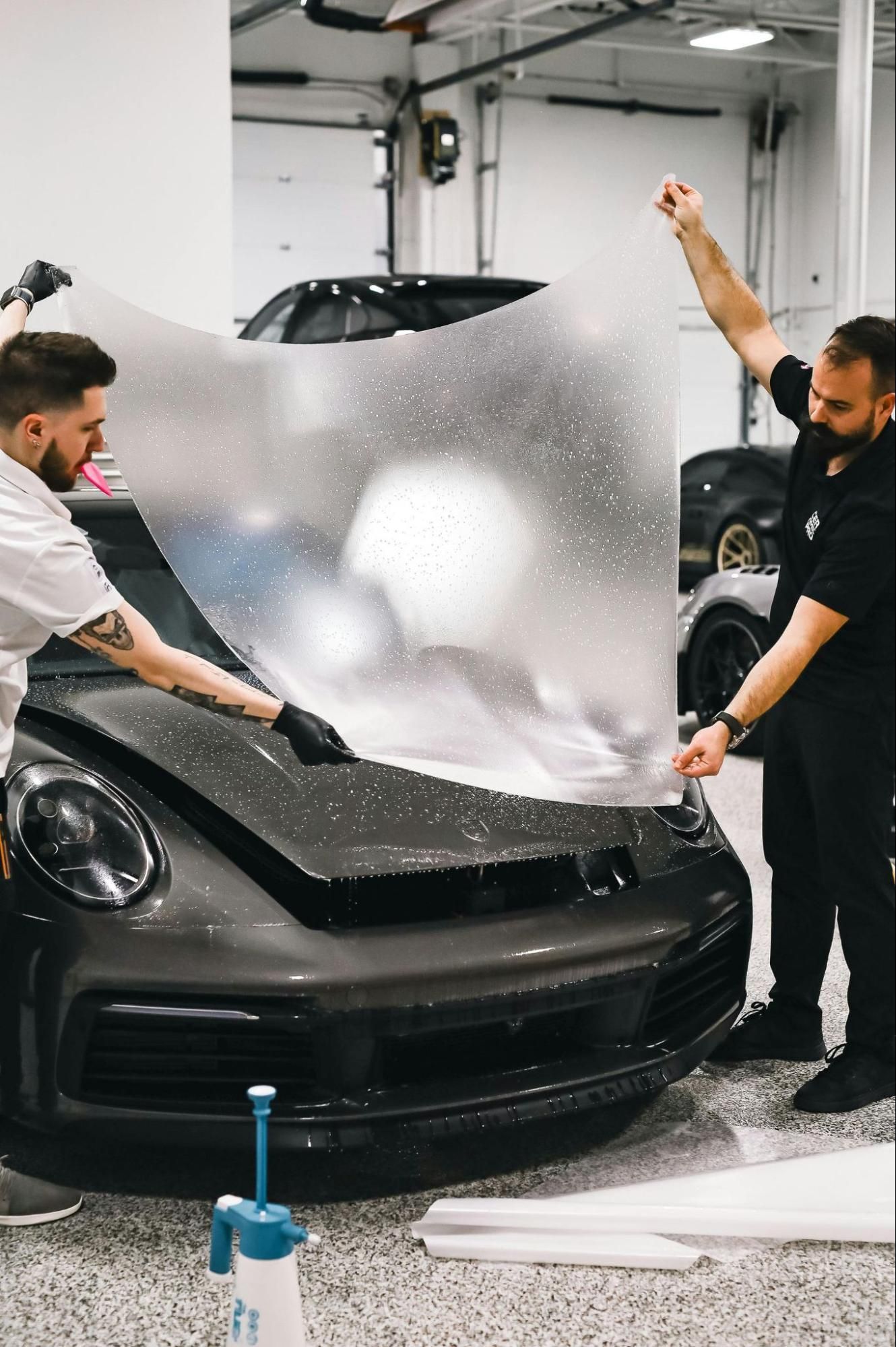 Professional installer applying paint protection film on car.