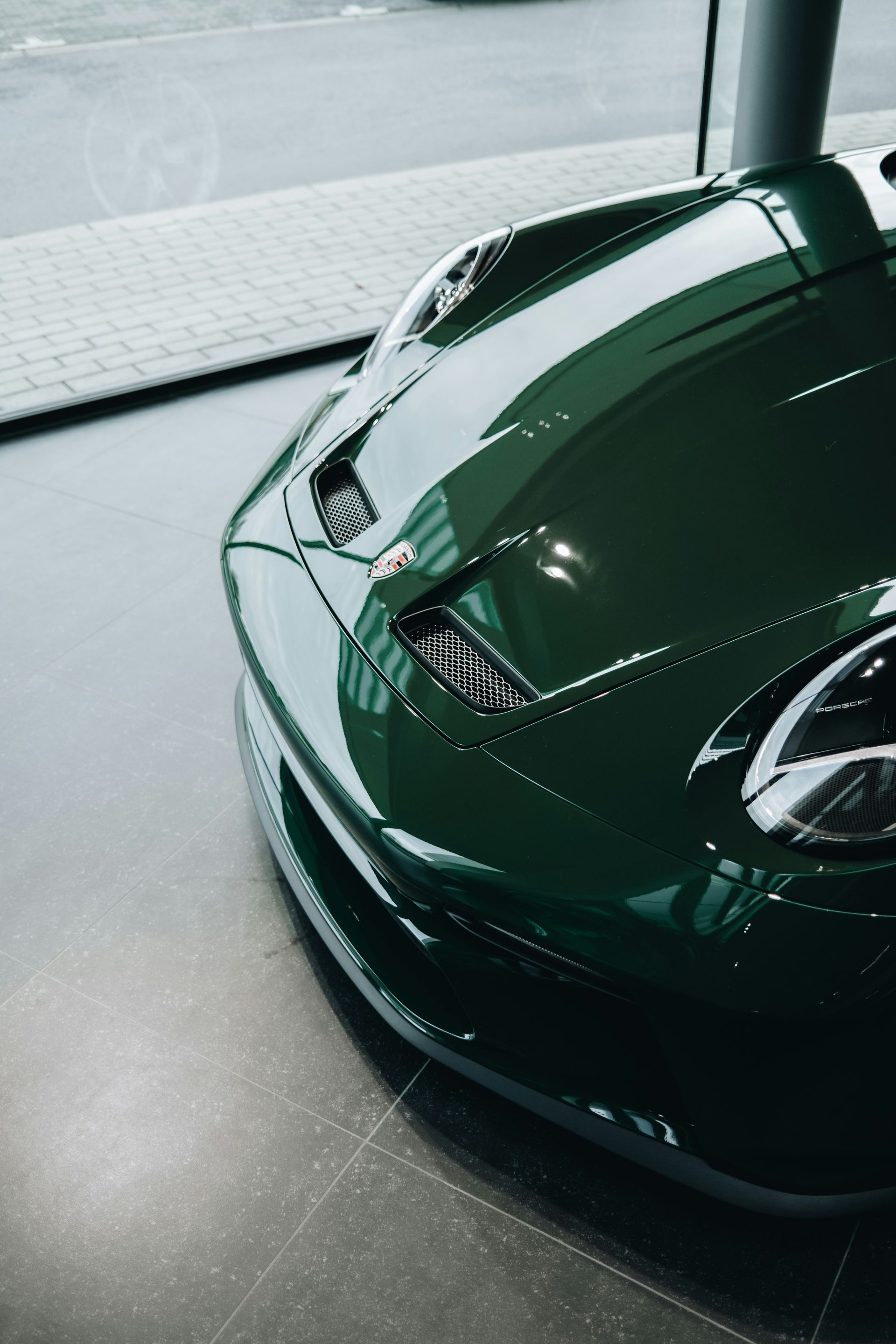 Green sports car, hood details visible: vents, sleek headlights, on display inside.