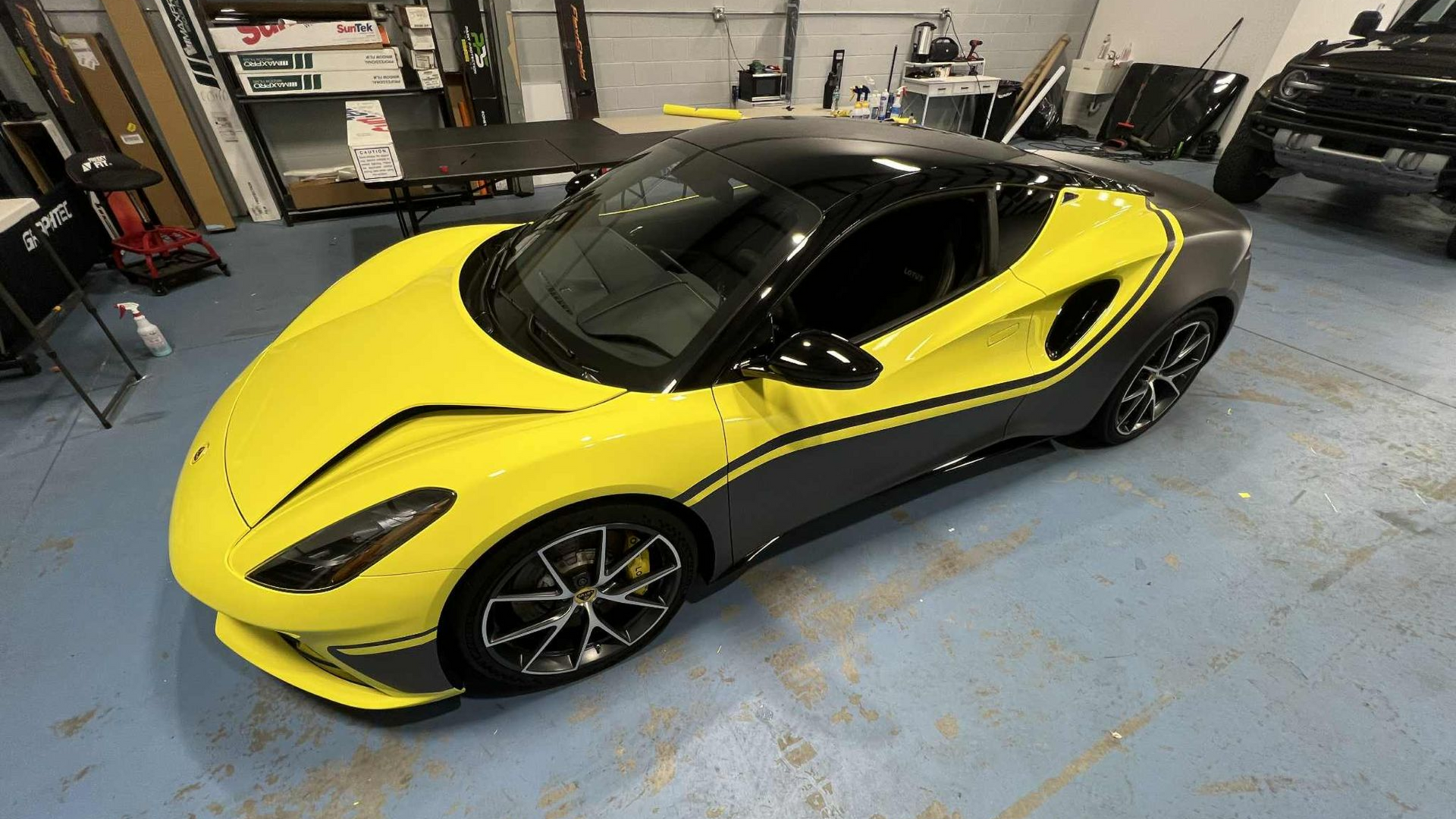 Yellow and gray sports car with black roof in a garage.