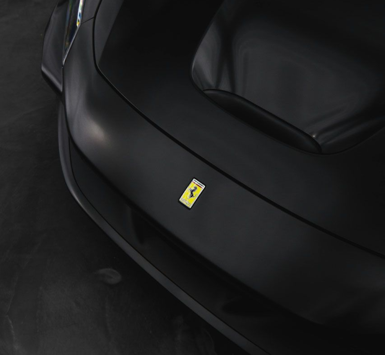 Matte black Ferrari car front, showing the logo.