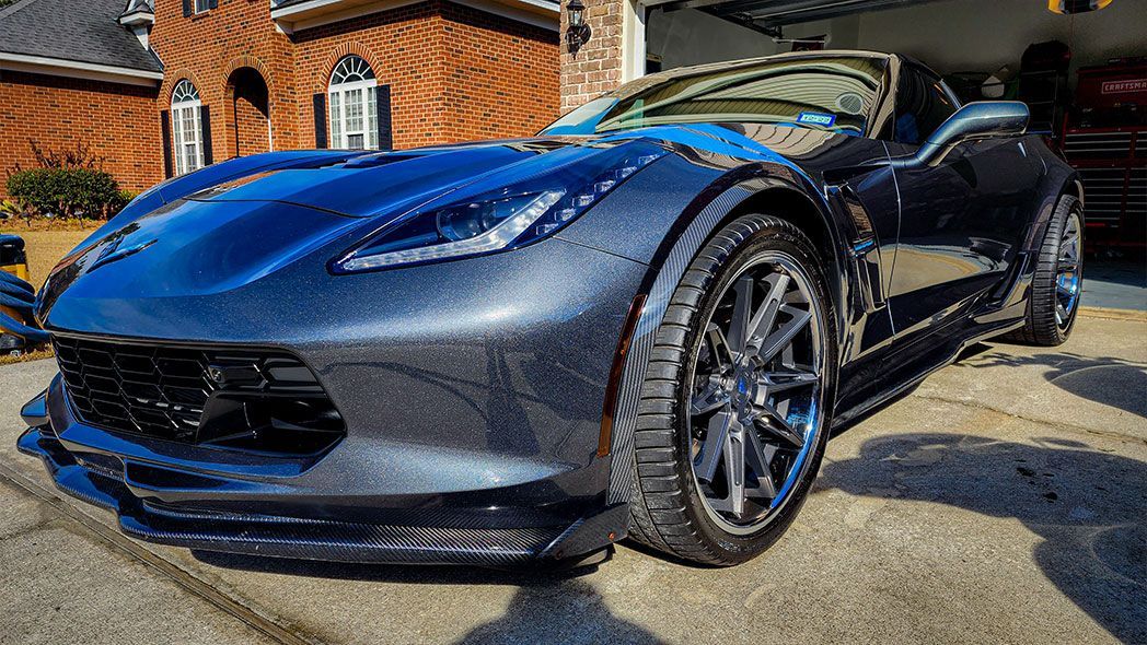 A blue sports car is parked in front of a house.