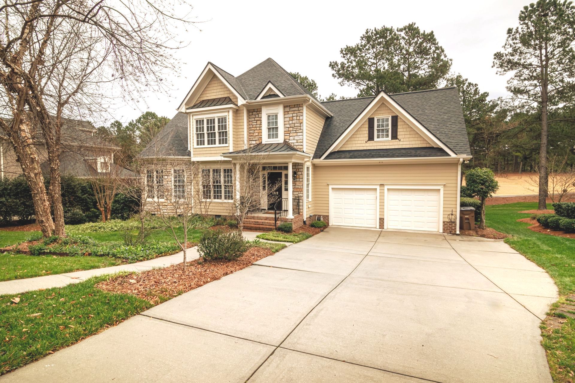 a large house with two garages and a driveway in front of it .