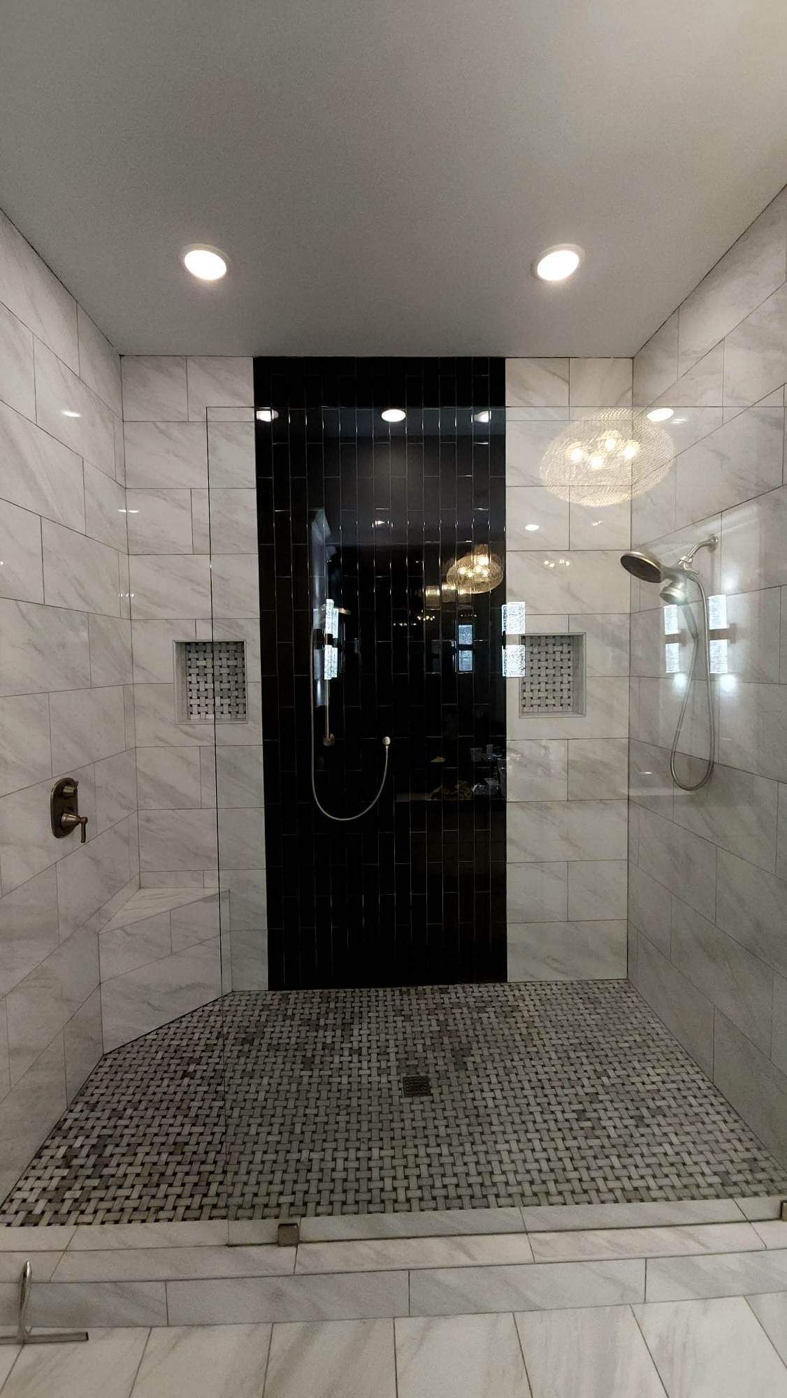 a bathroom with a walk in shower with a glass door .