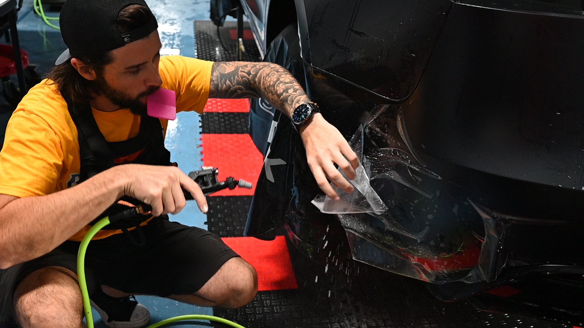 A man is wrapping a car with a hose.