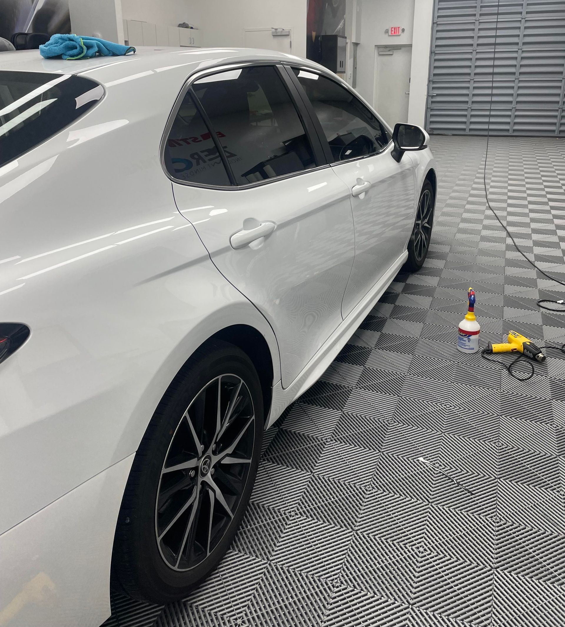 Man applying protective film to a truck headlight in a garage.