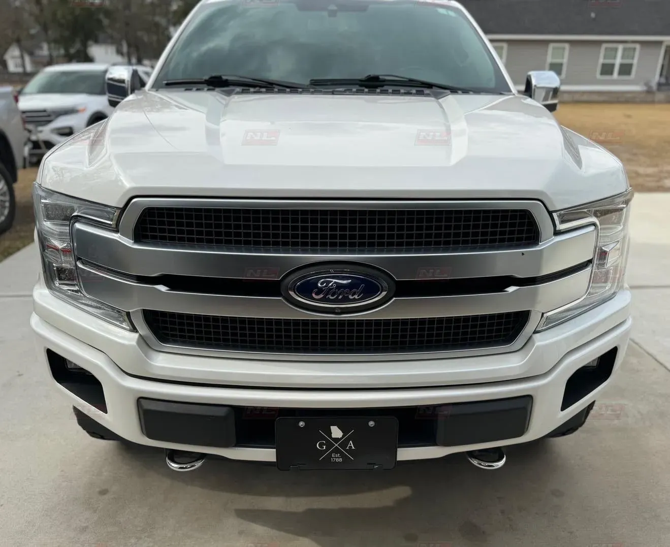 A white ford f150 truck is parked in a driveway in front of a house.