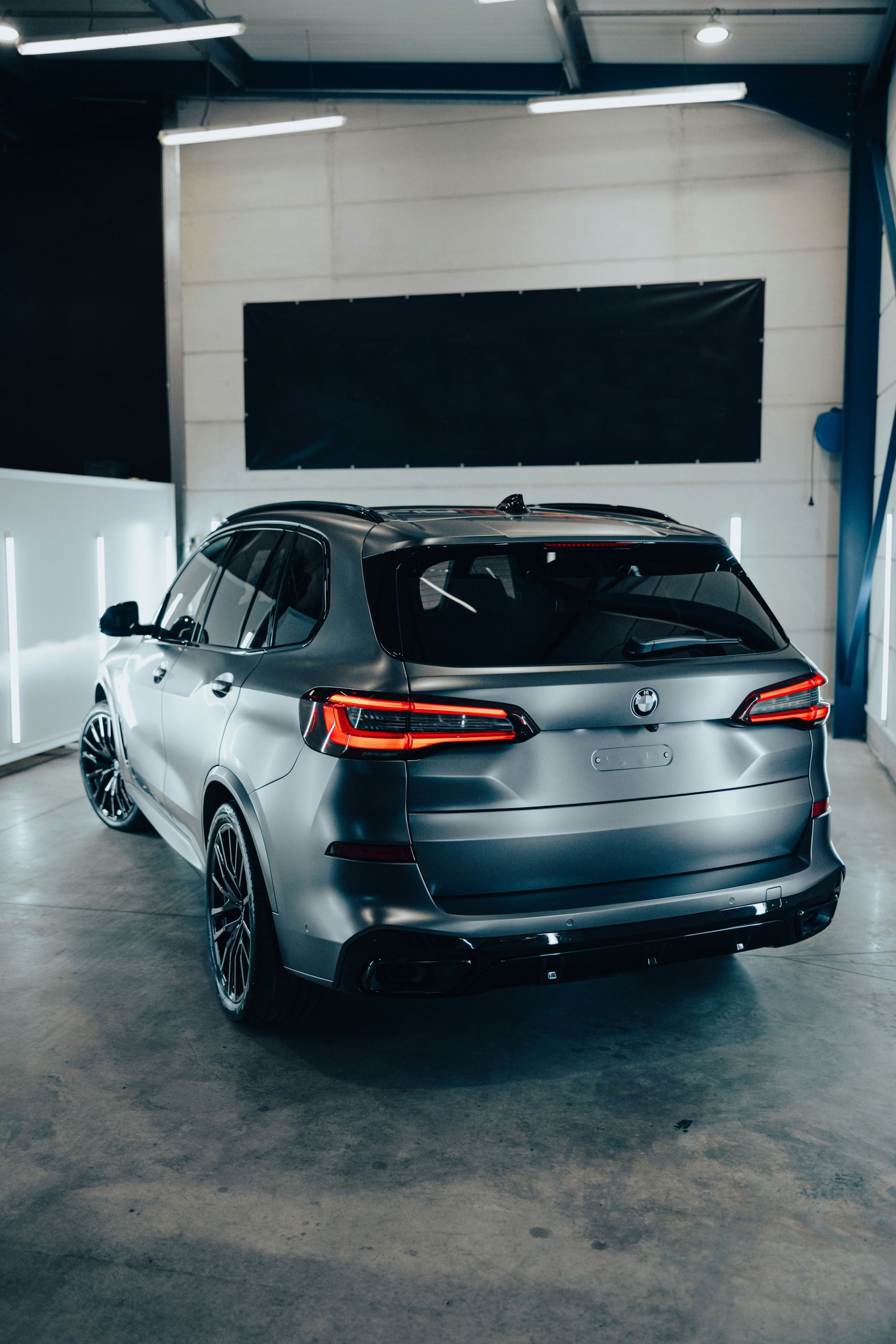 Gray SUV parked indoors with black accents, bright lights, concrete floor.