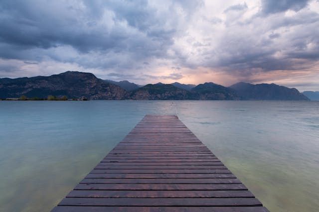 Quiet lakeside pier toward distant mountains creates a calm scene for cremation services Chaska, MN
