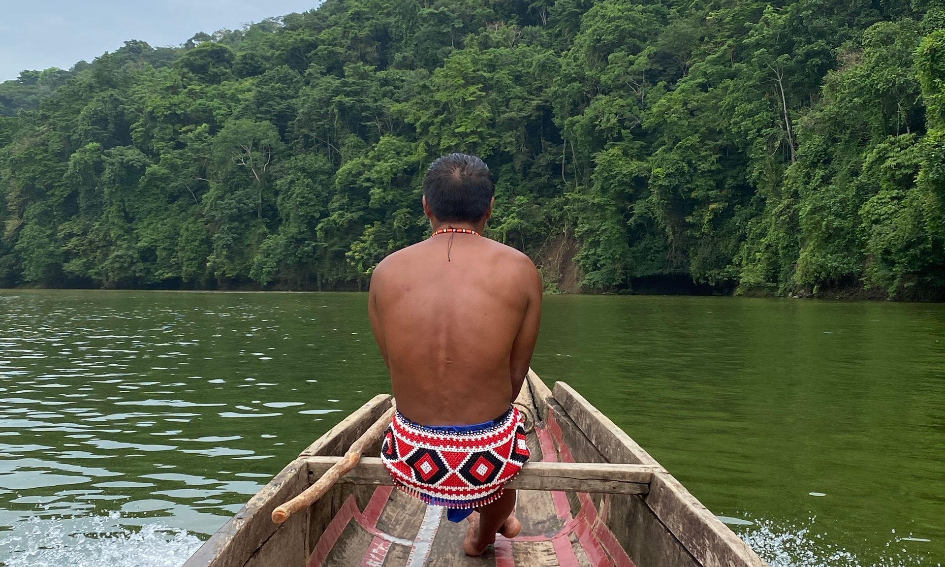 A man in a boat on the Chagres river, forest in the background.