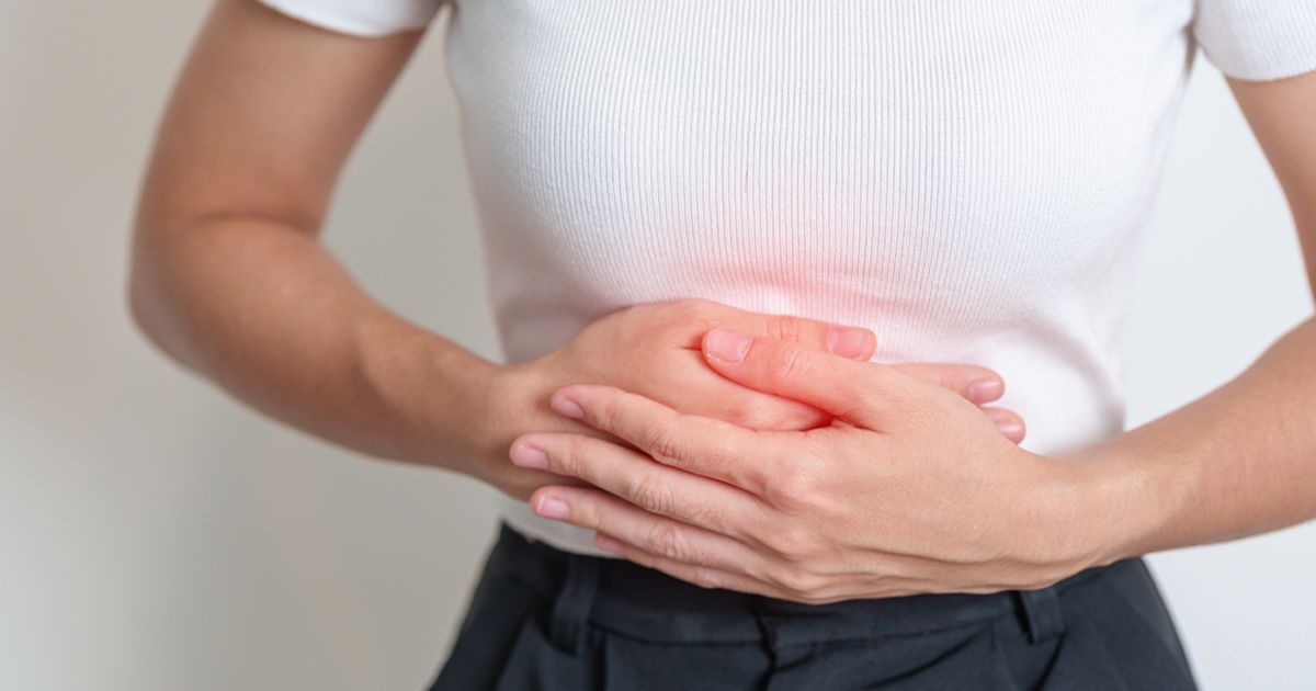 A woman is holding her stomach in pain. Acupuncture for Digestive Disorders NYC by Marc Bystock L.Ac.