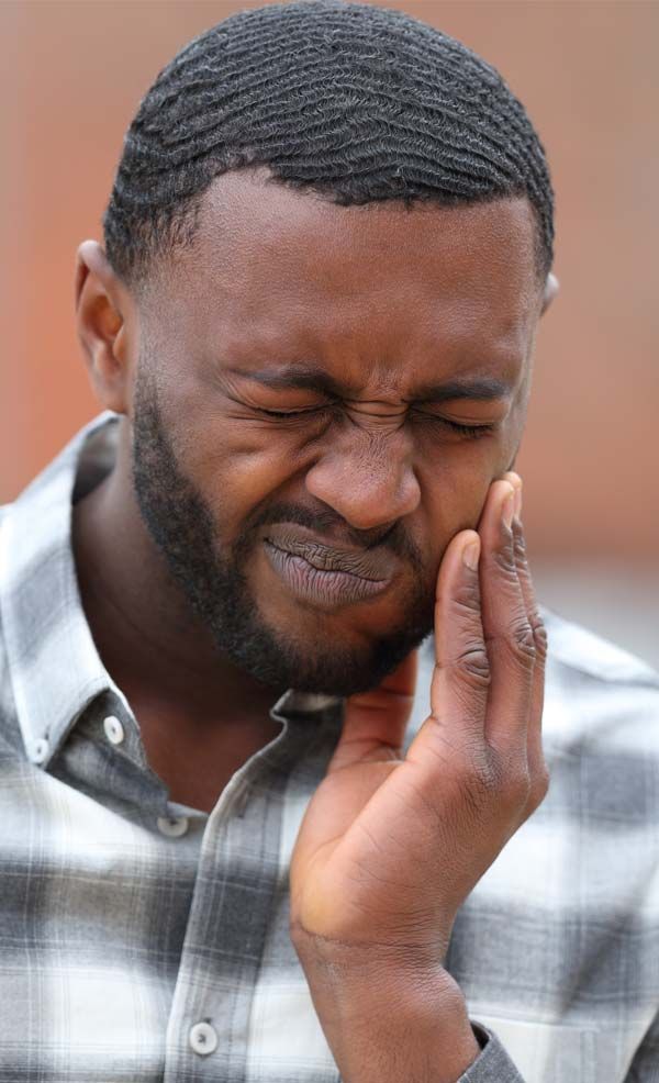 Man wearing a plaid shirt, grimacing and holding his cheek, indicating pain in need of Temporomandibular Joint Pain Relief Acupuncture Treatments by Marc Bystock, NYC Acupuncturist in Midtown Manhatta,n NY 10016