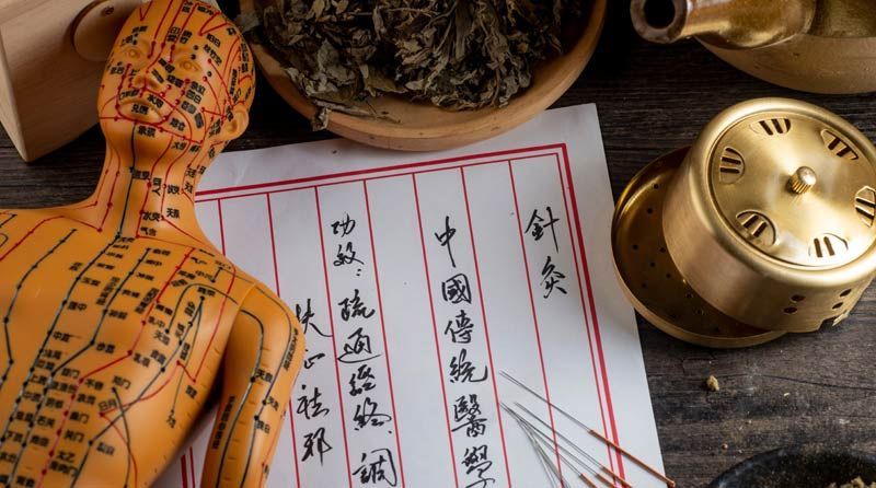 A wooden table topped with chinese writing representing Traditional Chinese Medicine Principals