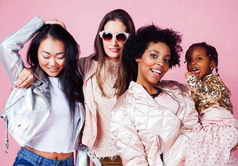 A group of women is posing for a picture together on a pink background representing Acupuncture and